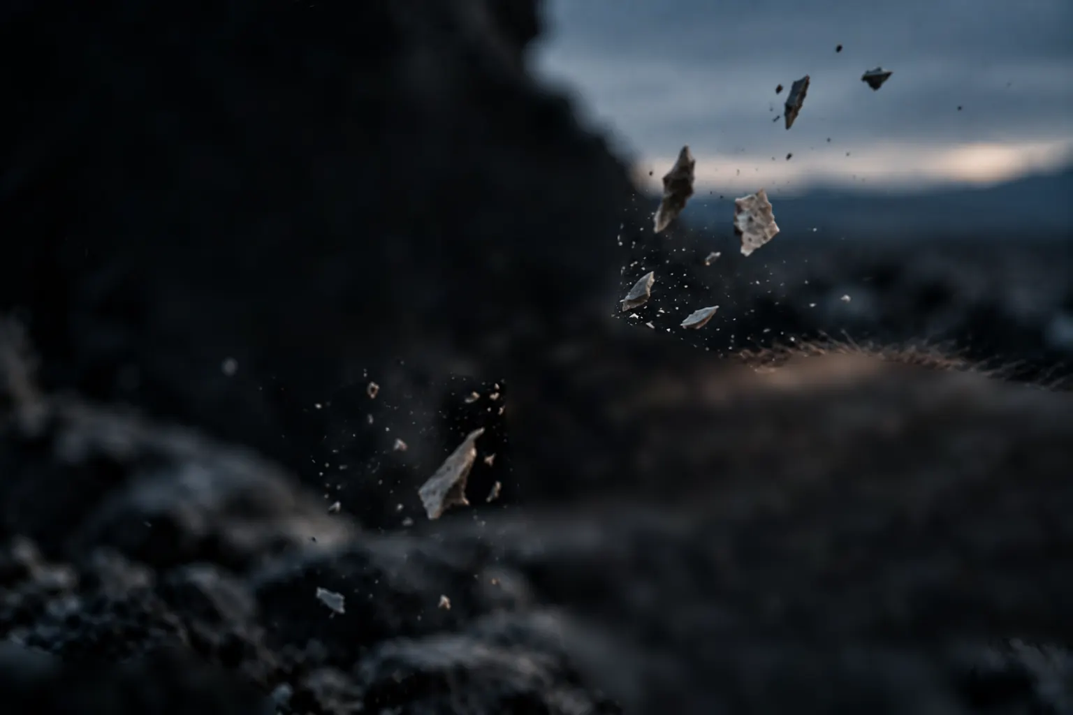 Two weathered hands strike one river stone against another; flakes fly.